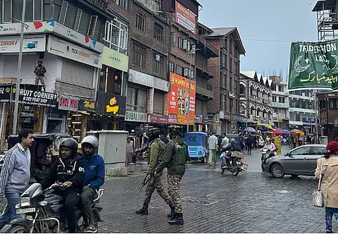 Two military personnel patrol Lal Chowk in Srinagar, Jammu and Kashmir, holding semi-automatic weapons in April 2025.