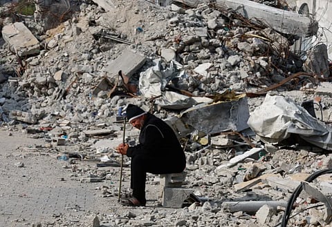 A Palestinian man sits near the rubble of a house destroyed in an Israeli strike in Rafah on January 9, 2024. Al-Jazeera via Mohammed Salem/ Reuters
