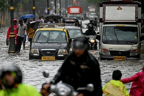 يتجول المسافرون عبر شارع غمرته المياه أثناء هطول أمطار غزيرة في مومباي في 18 أغسطس 2025. الصورة: وكالة فرانس برس