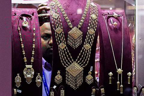 صائغ يُرتّب قطعًا ذهبيةً معروضةً. الصورة: وكالة فرانس برس