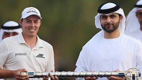 منصور بن محمد بن راشد يقدم كأس بطولة العالم للجولف إلى مات فيتزباتريك الذي حقق فوزًا مثيرًا في المباراة الفاصلة على روري ماكلروي في عقارات جميرا للجولف يوم الأحد. - صورة من بطولة العالم للجولف/ ريتشارد هيثكوت