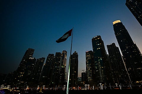 علم وطني لدولة الإمارات يرفرف على سارية أمام أفق وسط مدينة دبي.