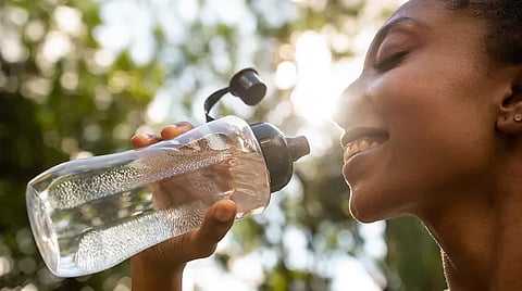 Woman drinking from a reusable water bottle.
