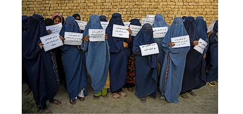 Afghan burqa-clad women hold placards as they protest for their right to education, in Mazar-i-Sharif on August 12, 2023