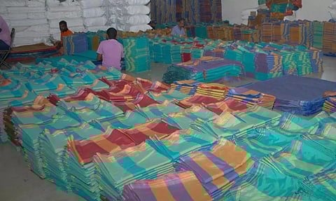 இலவச வேட்டி, சேலை அனுப்புவதற்கு தயார் நிலையில் வைக்கப்பட்டு உள்ளதை படத்தில் காணலாம்.