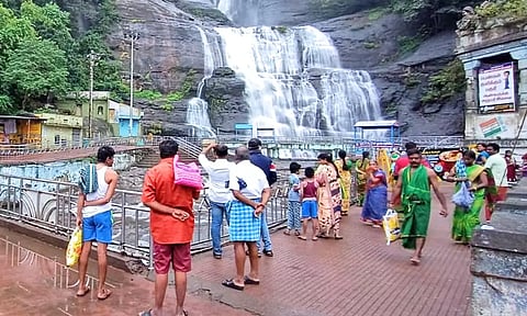 குற்றாலம் மெயினருவியில் வெள்ளம் ஆர்ப்பரித்து கொட்டுவதால் குளிக்க வந்த சுற்றுலா பயணிகள் ஏமாற்றத்துடன் நிற்கும் காட்சி.