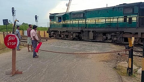 சேதம் அடைந்த ரெயில்வே கேட்டில் செயினை கட்டி வாகனங்களை நிறுத்திய பணியாளர்கள்.