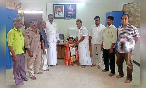 சிறுமி ஆருண்யாவிற்கு மங்கலம் ஊராட்சி மன்றத்தலைவர் எஸ்.எம்.பி.மூர்த்தி வாழ்த்து தெரிவித்த காட்சி.