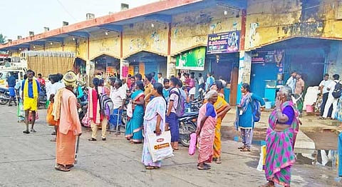 பஸ்சேவை குறைக்கப்பட்டதால் நிலக்கோட்டை பஸ் நிலையத்தில் காத்திருக்கும் பயணிகள்.