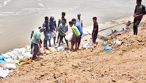கரையோர பகுதிகளில் உடைப்பை தடுக்க மணல் மூட்டைகளை அடுக்கும் பணியில் கிராம மக்கள்.