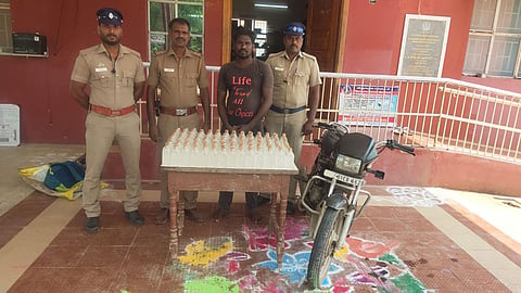 மதுபாட்டில்கள் கடத்தியதாக கைதான வாலிபரைபடத்தில் காணலாம்.