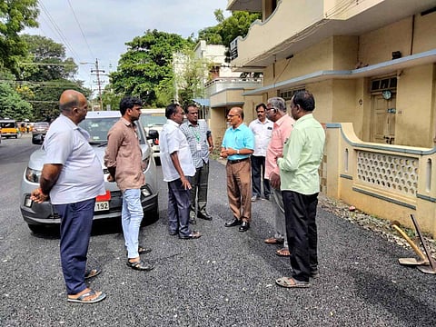 மின்கம்பத்தை மாற்றி அமைக்கும் பணியை அதிகாரிகள் ஆய்வு செய்த காட்சி.