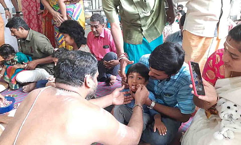 குழந்தைகளுக்கு அர்ச்சகர்கள் தங்க வேலால் நாக்கில் எழுதிய காட்சி.