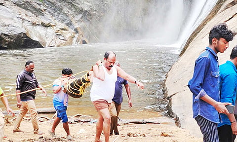 அருவியில் விழுந்த மாணவனின் உடலை தீயணைப்பு துறையினர் மற்றும் மீட்பு குழுவினர் மீட்டு வந்த காட்சி.