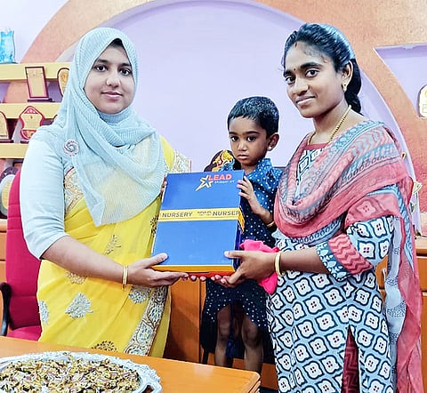 பள்ளியின் முதல்வர் சமீமா பர்வீன் குழந்தைக்கு பாடப் புத்தகம் வழங்கினார்.