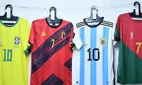 கால்பந்து போட்டி ரசிகர்கள் அணிவதற்காக திருப்பூரில் தயாரிக்கப்பட்டுள்ள டீ-சர்ட் பனியன்கள்.