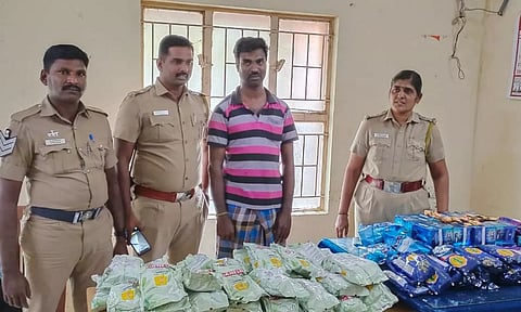 கைது செய்யப்பட்ட கிருஷ்ணராஜா மற்றும் பறிமுதல் செய்யப்பட்ட குட்கா பொருட்களுடன் போலீசார்.