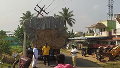 லாரி மீது மின் கம்பம் சாய்ந்து கிடக்கும் காட்சி.