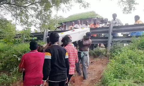 தடுப்பு கம்பிகளை தாண்டி இறந்தவரின் உடலை எடுத்து செல்லும் பொதுமக்கள்.