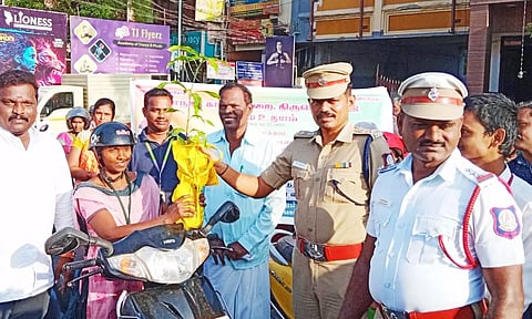 ஹெல்மெட் அணிந்து வாகனம் ஓட்டி வந்த பெண்ணுக்கு மாநகர போலீஸ் துணை கமிஷனர் சீனிவாசன் துணிப்பை, மரக்கன்றுகளை வழங்கிய காட்சி.