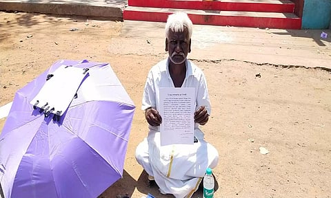 கலெக்டர் அலுவலகம் அருகே உள்ள ஆஞ்சநேயர் கோவில் தரையில் அமர்ந்து நாராயணன் போராட்டம் செய்த காட்சி.