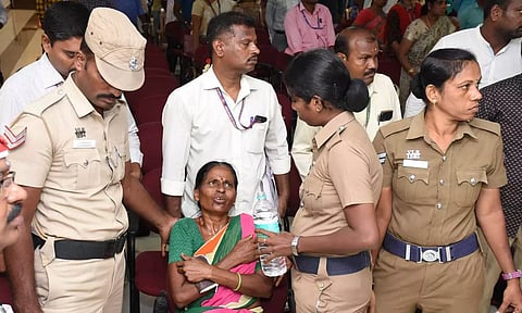 மயங்கி விழுந்த பெண்ணிற்கு தண்ணீர் கொடுத்த போலீசார்.