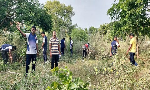 விளையாட்டு மைதானத்தை தூய்மைபடுத்தும் பணியில் ஈடுபட்டுள்ள போலீசாரை படத்தில் காணலாம்.