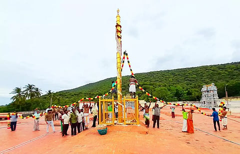 கள்ளழகர் கோவில் ஆடித்திருவிழா கொடியேற்றத்தை முன்னிட்டு கொடிமரம் வண்ண மலர்கள் கொண்ட மாலைகளால் அலங்கரிக்கப்பட்ட காட்சி.