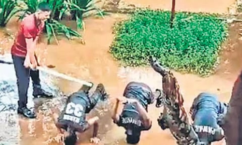 கொட்டும் மழையில் என்.சி.சி. மாணவர்களை தரையில் குப்புற படுக்க வைத்து சீனியர் மாணவர் கம்பால் தாக்கும் காட்சி.