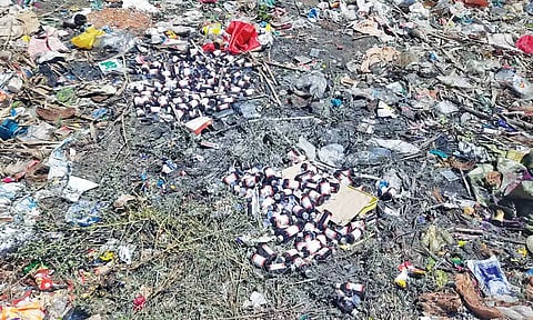 குப்பை தொட்டியில் கிடந்த காலாவதியான அரசு சத்து டானிக் பாட்டில்கள்.