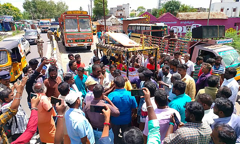 இறந்த மூதாட்டியின் உடலுடன் மறியல் போராட்டத்தில் ஈடுபட்டவர்களை படத்தில் காணலாம்.