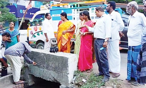 இடையூறாக உள்ள கல்வெட்டை அளவீடு செய்யும் அதிகாரிகள்.