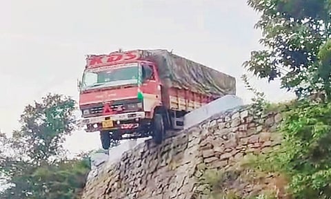 தடுப்பு சுவரை இடித்து அந்தரத்தில் தொங்கிய சரக்கு வேன்