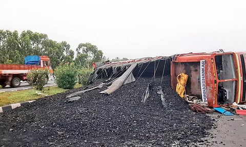 சாலையின் நடுவே கவிழ்ந்த லாரியை படத்தில் காணலாம்.