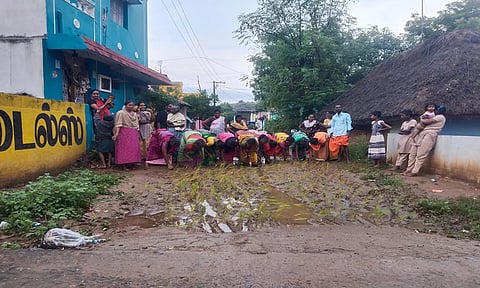சாலையில் நாற்று நடும் பொதுமக்களை படத்தில் காணலாம்.