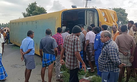 கல்லூரி பஸ் சாலையில் கவிழ்ந்து கிடப்பதை காணலாம்