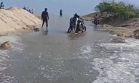 கடல் நீர் வெளியேறியதால் பழவேற்காடு- காட்டுப்பள்ளி சாலை மணலால் மூடியது