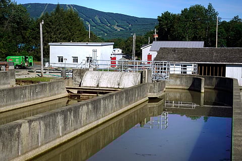 The Okemo ski resort is visible in the distance from a defunct wastewater treatment tank in Ludlow, Vt. July’s floodwaters washed sewage from the ditches into the river, and only one has been repaired and is functioning.