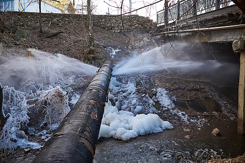 The water has frozen into chunks of ice near a small flowing stream, highlighting a significant water loss event.