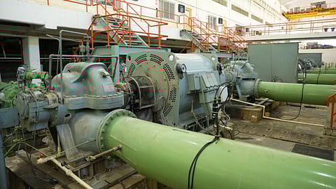 Wide view of an industrial water pumping station with multiple large green pumps equipped with digital monitoring systems