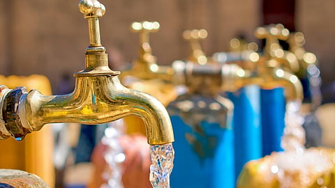 Close-up of a rusted public metal tap with water flowing out, depicting municipal water supply infrastructure in Chennai.