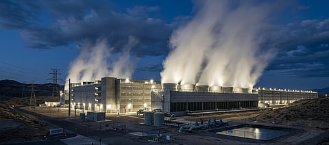 Large industrial cooling towers emitting heavy water vapor outside a modern hyperscale data center facility at dusk