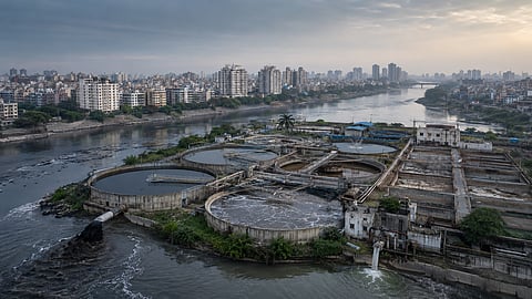 An urban sewage-treatment facility beside a polluted river and densely populated Indian city, representing India’s widening wastewater-treatment capacity gap.