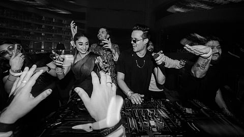 An international DJ performing at a luxury Indian wedding with festival-style lighting and a packed dance floor.