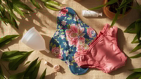 An artistic, informative flat lay image showcasing sustainable menstrual products popular in India_ a menstrual cup made of translucent silicone, colorful reusable cloth pads made of cotton with floral prints