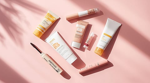 Minimal summer beauty essentials including sunscreen, BB cream, kajal, mascara, and lip balm arranged neatly on a pastel background for a quick everyday routine.