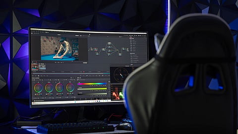 Video editing software running on a monitor with colour grading tools and editing timeline displayed