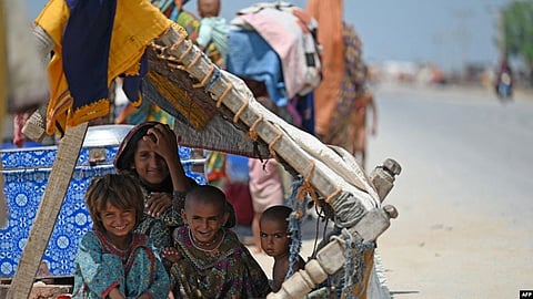 Internally displaced flood-affected children rest under makeshift shelter along a road on higher ground in a flooded area after heavy monsoon rains on the outskirts of Jacobabad, Sindh province, Sept. 6, 2022. (Image Source- VOA)