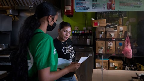 Melissa Lopez explains the covid testing process to a taco shop employee in Fresno, California, as part of her training as a health educator.