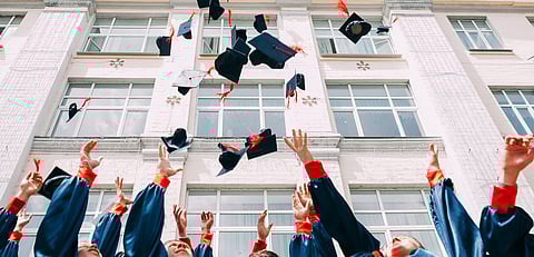 A group of students flying their graduation hats in the air as part of a celebration.